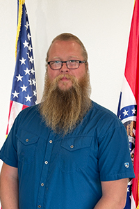 Josh Billingsley standing in front of the American and Missouri flags